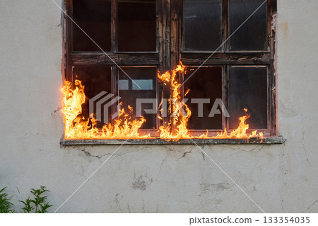 Old wooden window on fire, flames engulfing frame, dangerous situation, destruction and damage, burning house, emergency incident, dramatic scene, outdoor setting Old wooden window on fire, flames engulfing frame, dangerous situation, destruction and damage, burning house, emergency incident, dramatic scene, outdoor setting 133354035