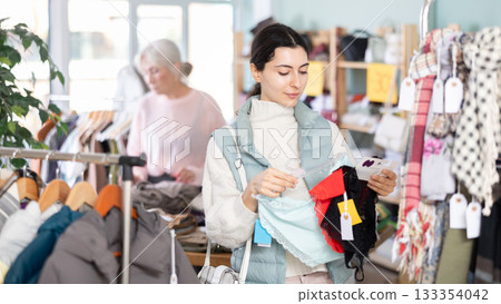 Young woman chooses panties in clothing store Young woman chooses panties in clothing store 133354042