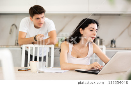 Young guy quarrels with young woman working at laptop Young guy quarrels with young woman working at laptop 133354048