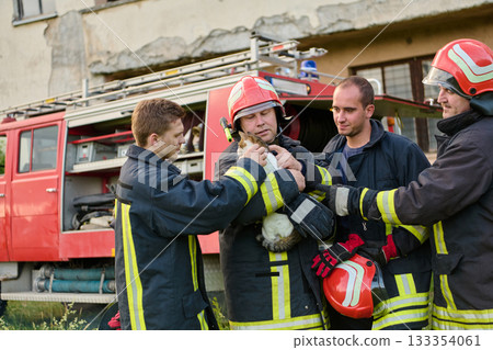 Firefighters rescuing a cat from a building, firemen in uniform with helmets saving animal, emergency service team helping pet, fire truck in background, rescue operation, heroes. 133354061