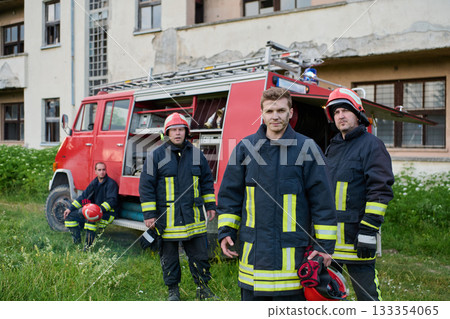 Firefighters in uniform and helmets posing in front of fire truck, emergency service team, rescue operation, fire safety, urban scene, outdoor, teamwork and bravery concept 133354065