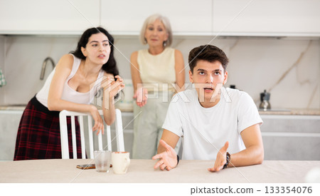 Upset and unhappy son-in-law sitting in the kitchen separately, family conflict Upset and unhappy son-in-law sitting in the kitchen separately, family conflict 133354076