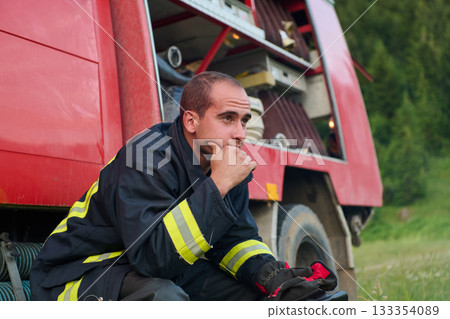 Thoughtful Firefighter in Uniform Sits on Firetruck, Contemplating Rescue Operations, Emergency Services, Fire Safety, Training, and Community Support, Surrounded by Nature Thoughtful Firefighter in Uniform Sits on Firetruck, Contemplating Rescue Operations, Emergency Services, Fire Safety, Training, and Community Support, Surrounded by Nature 133354089
