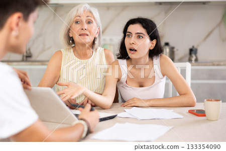 Elderly and young female clients listen attentively and intently to male seller Elderly and young female clients listen attentively and intently to male seller 133354090