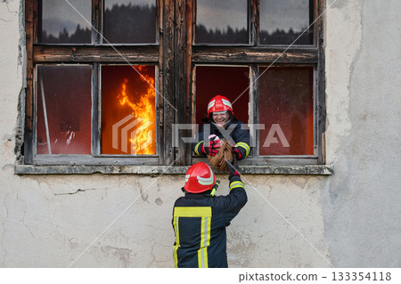 Firefighter rescuing a baby from burning building, fireman in action saving child, emergency situation, fire in house, danger, rescue operation, outdoor scene Firefighter rescuing a baby from burning building, fireman in action saving child, emergency situation, fire in house, danger, rescue operation, outdoor scene 133354118
