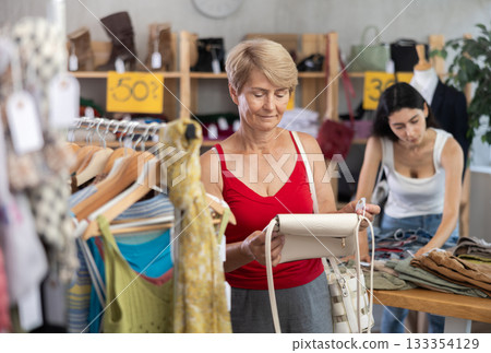 Mature woman choosing a handbag in a store Mature woman choosing a handbag in a store 133354129
