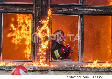 Firefighter rescuing a baby from burning building, fireman in action saving child, emergency situation, fire in house, danger, rescue operation, outdoor scene 133354166
