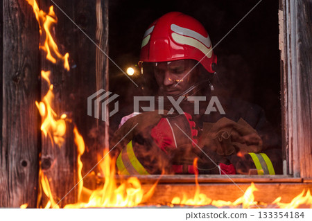 Firefighter rescuing a baby from burning building, fireman in action saving child, emergency situation, fire in house, danger, rescue operation, outdoor scene 133354184