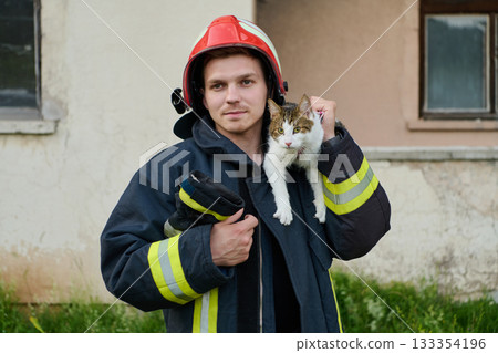Firefighter rescues a cat from a burning building, hero holding a rescued pet, rescue operation, urban scene, firefighter in uniform, saving animal, outdoor setting 133354196