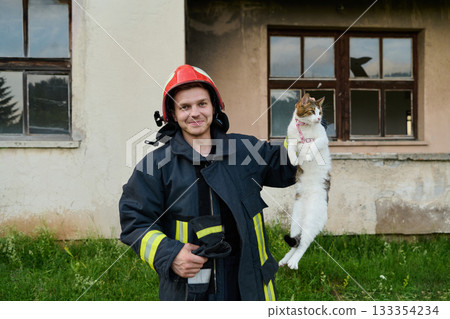 Firefighter rescues a cat from a burning building, hero holding a rescued pet, rescue operation, urban scene, firefighter in uniform, saving animal, outdoor setting 133354234