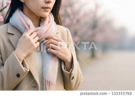 週五清晨，一位上班族女士在盛開著梅花的公園裡整理她的披肩。 133355768