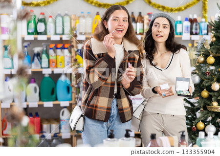Two girl friends choose eyeshadow and lip stick while shopping 133355904