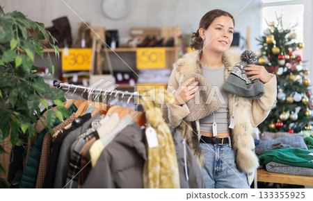 European girl near showcase pick out and buying hat, New Year eve European girl near showcase pick out and buying hat, New Year eve 133355925