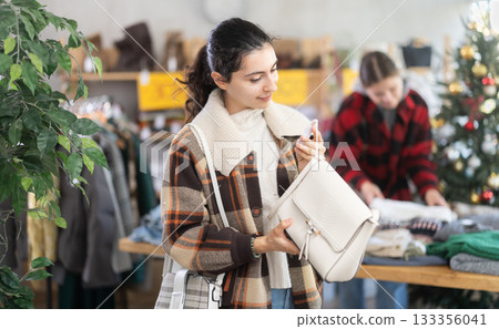Armenian woman stands in a shop decorated for Christmas and chooses a handbag 133356041