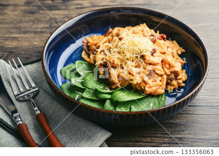 Close-up of Orzo pasta with sun-dried tomato,  chicken hard cheese and spinach 133356063