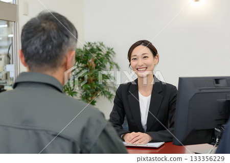 A Japanese woman consulting at a counter. A smile and a sense of trust in the customer service. 133356229
