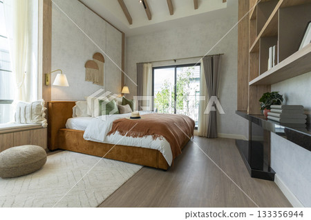 Big bedroom in cottage style with brown and green pillow. Wall lamp and wall art on wall. 133356944