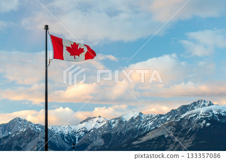 Canadian flag against a natural landscape of mountains and trees at sunset. 133357086