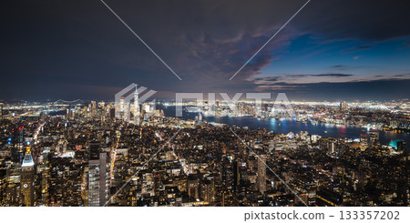 Night view of New York City skyline with glowing skyscrapers and reflections on the Hudson River 133357202