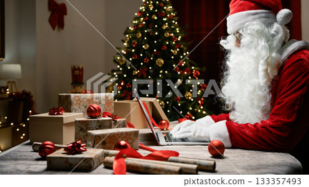 Santa Claus writing on Pc under Christmas tree 133357493