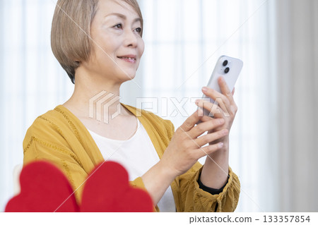 一位老年婦女正在使用智慧型手機上的配對應用程式 一位老年婦女正在使用智慧型手機上的配對應用程式 133357854