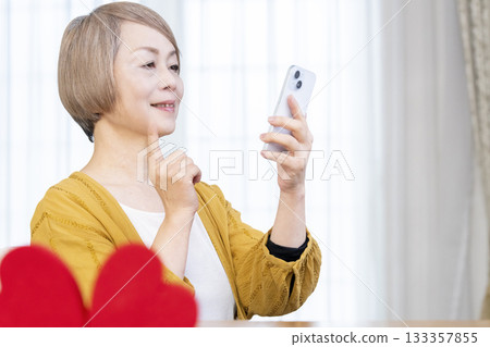 一位老年婦女正在使用智慧型手機上的配對應用程式 133357855