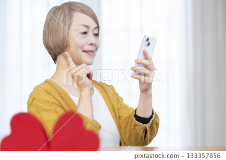 一位老年婦女正在使用智慧型手機上的配對應用程式 133357856