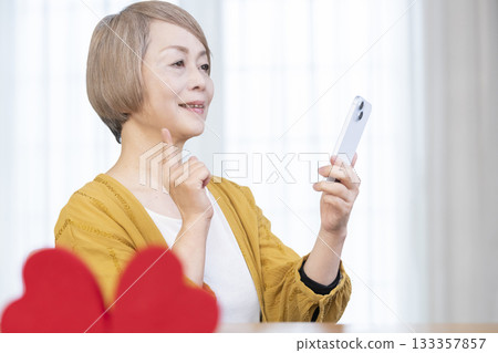 一位老年婦女正在使用智慧型手機上的配對應用程式 一位老年婦女正在使用智慧型手機上的配對應用程式 133357857