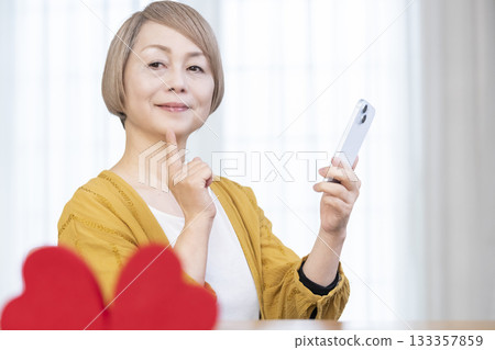 一位老年婦女正在使用智慧型手機上的配對應用程式 一位老年婦女正在使用智慧型手機上的配對應用程式 133357859