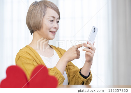 一位老年婦女正在使用智慧型手機上的配對應用程式 133357860
