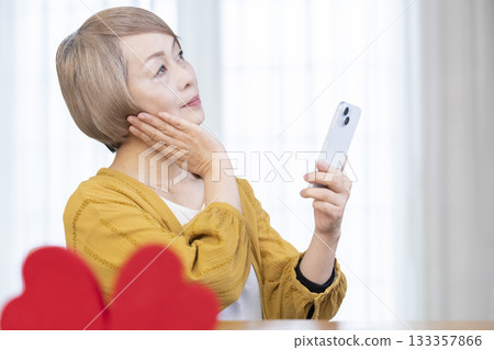 一位老年婦女正在使用智慧型手機上的配對應用程式 133357866