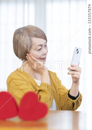 一位老年婦女正在使用智慧型手機上的配對應用程式 133357874