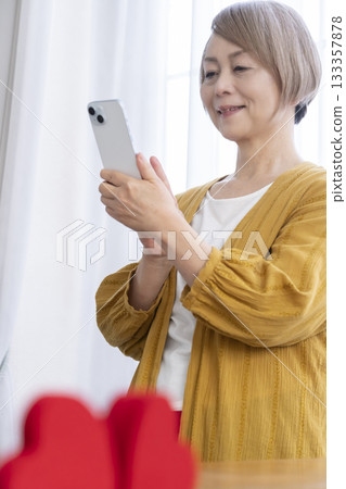 一位老年婦女正在使用智慧型手機上的配對應用程式 133357878