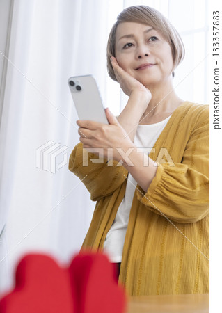 一位老年婦女正在使用智慧型手機上的配對應用程式 一位老年婦女正在使用智慧型手機上的配對應用程式 133357883
