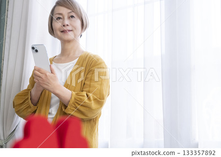 一位老年婦女正在使用智慧型手機上的配對應用程式 133357892