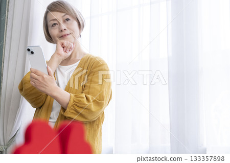 一位老年婦女正在使用智慧型手機上的配對應用程式 133357898