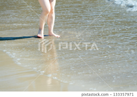 Young woman walking on the seashore, white waves, clear skies, seaside, bare feet, beautiful, ideal, holiday, vacation, beach, woman 133357971
