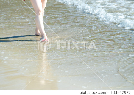 Young woman walking on the seashore, white waves, clear skies, seaside, bare feet, beautiful, ideal, holiday, vacation, beach, woman 133357972