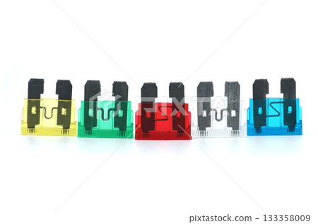 Colorful automotive fuses arranged in a row against a clean white background 133358009