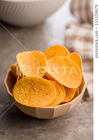 Crispy potato chips in bowl on kitchen table. 133359679