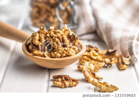 Peeled walnut kernels on wooden spoon on white table. 133359683