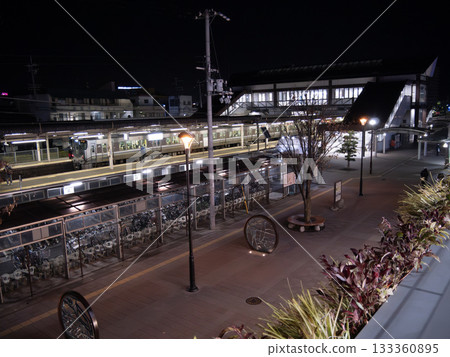 Night view of a train stopping at a suburban station and the station square 133360895