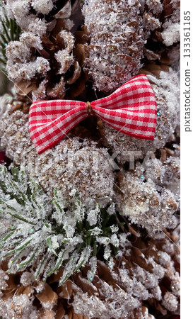 Frosted pine cones, red gingham bow, and berries creating a rustic Christmas background 133361185