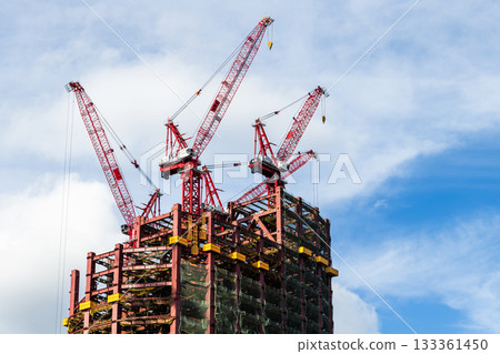 Low-angle view of cranes and steel structures of building construction with a blue sky background in Taiwan. Low-angle view of cranes and steel structures of building construction with a blue sky background in Taiwan. 133361450