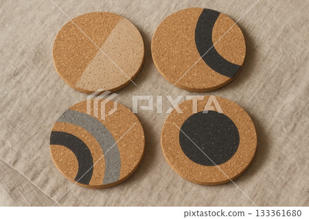 Set of round cork coasters with geometric patterns on fabric background, eco home decor and minimalist natural design concept. Set of round cork coasters with geometric patterns on fabric background, eco home decor and minimalist natural design concept. 133361680