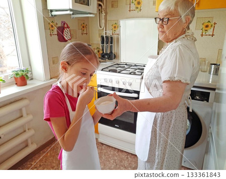 A grandmother and her granddaughter set out the necessary ingredients for cooking on the table. 133361843