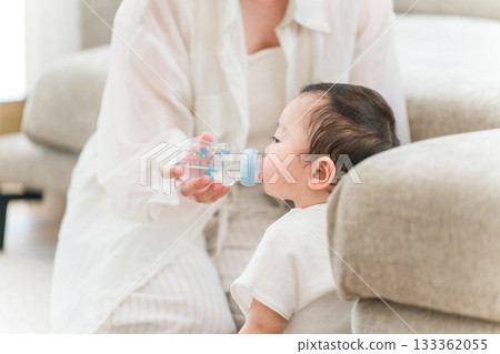 母親在家裡的客廳用奶瓶餵寶寶水。 133362055