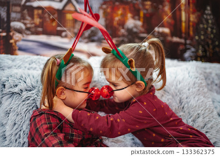 Two young girls wearing reindeer Christmas costumes playing together Two young girls wearing reindeer Christmas costumes playing together 133362375