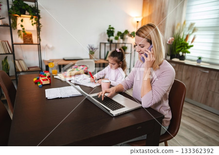 Busy mother balances work and parenting at home office space 133362392