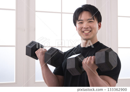 A man in his 20s doing muscle training with dumbbells A man in his 20s doing muscle training with dumbbells 133362900